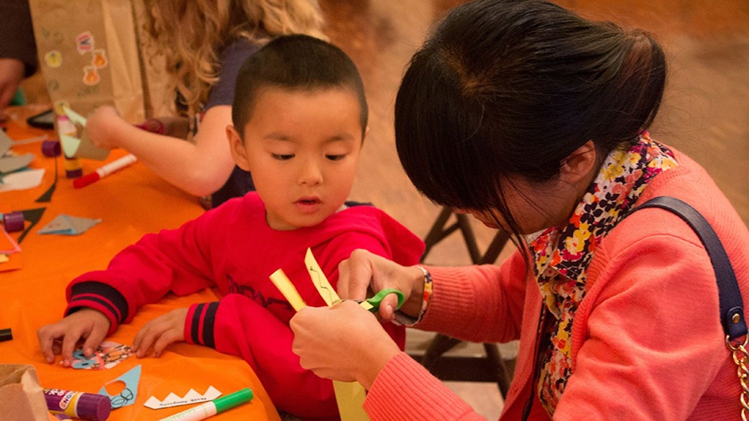 Luming Xu helps her son Yoyo cut out teeth for a monster bookmark at the Mathers Museum's Halloween Family Fun Fest on Oct. 26.