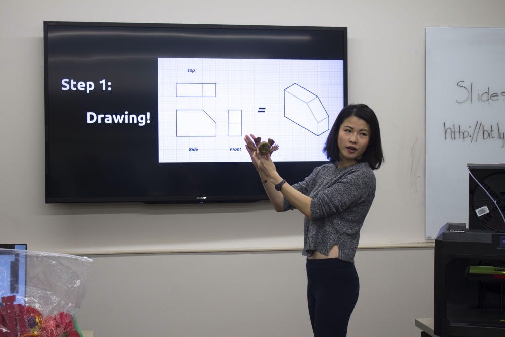 Joey Huang, lead intern for CEWiT's 3D printing special interest group, explains a step in the 3D printing process during a CEWiT workshop. The workshop focused on Halloween themed designs on Monday at Wells Library.