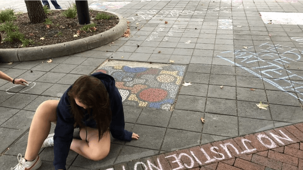 A protester chalks &quot;No justice, no peace&quot; at People&#x27;s Park Sept. 23 after only one officer in the Breonna Taylor case was indicted.