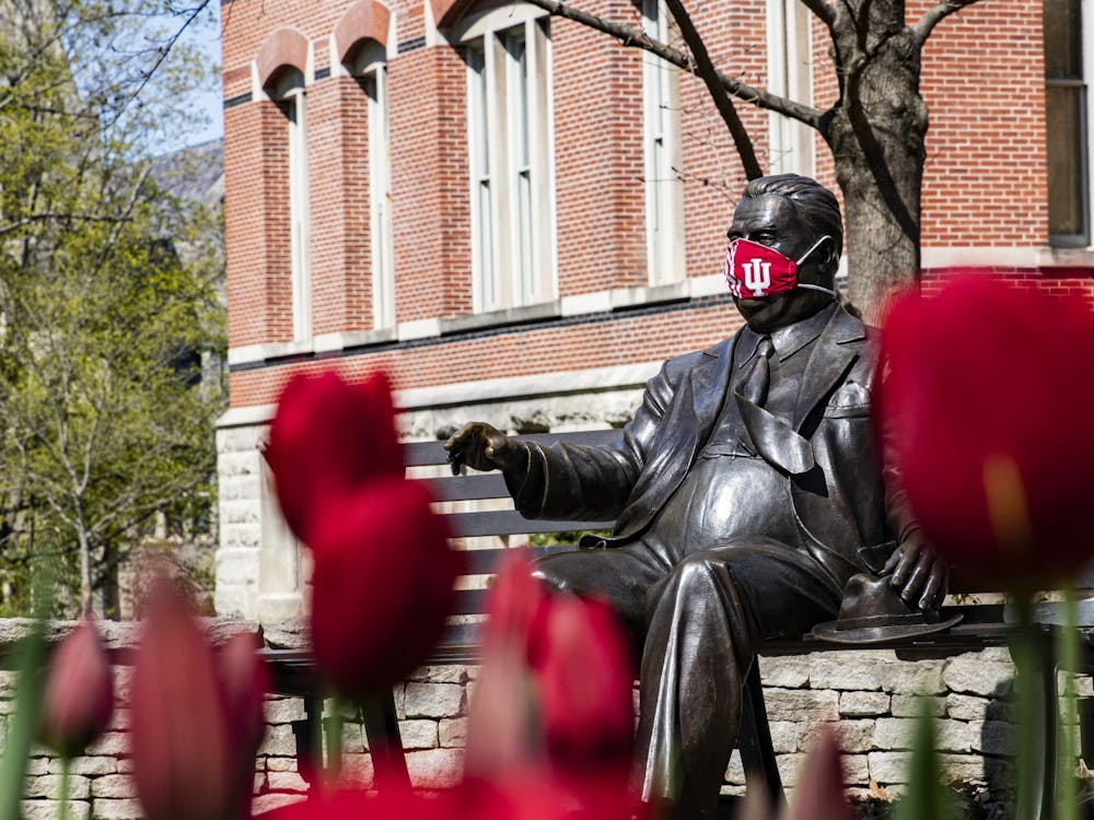 A mask covers the face of the Herman B Wells statue April 20 on IU’s campus.