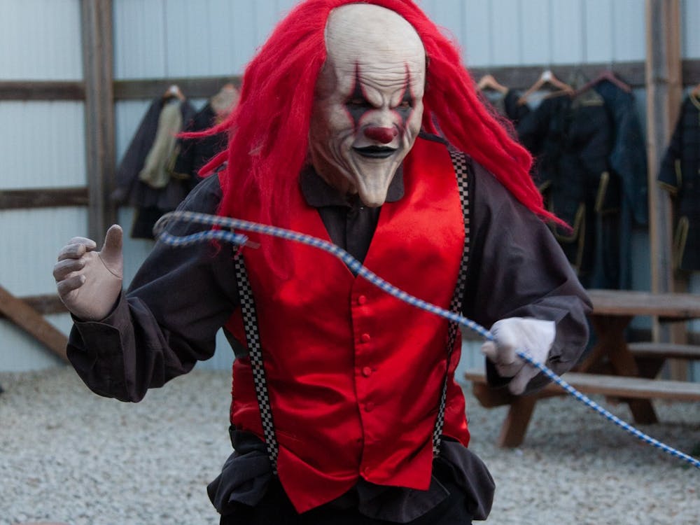 A masked clown poses after getting in costume the evening of Oct. 23, 2022, at Indy Scream Park. Jodi Morgan, the park&#x27;s head makeup manager, said her team applies dark makeup around the eyes of actors who wear masks to make them look more realistic.﻿