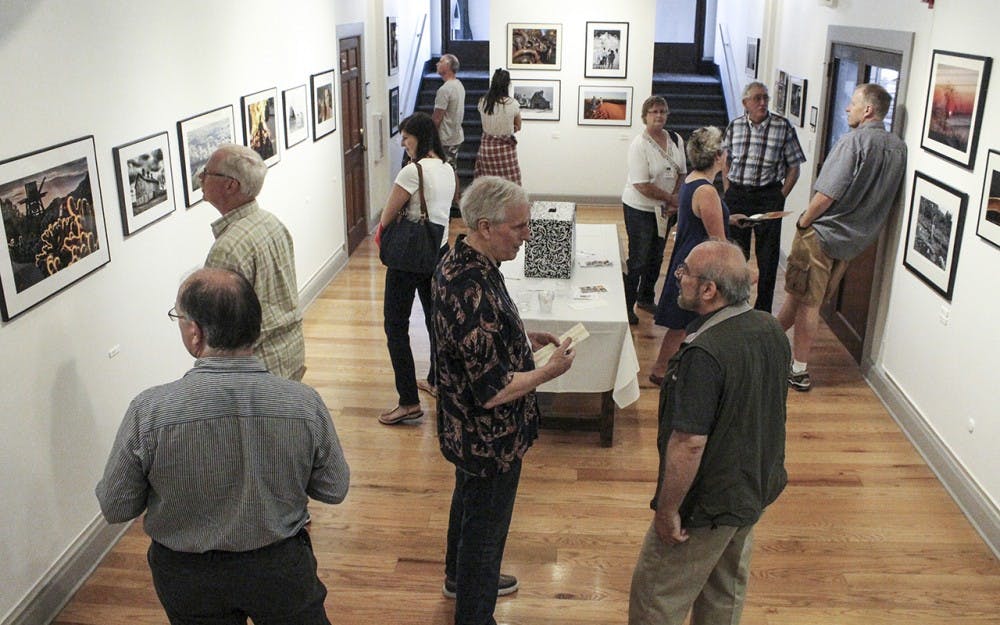 7月5日星期五，人们聚集在常春藤理工约翰·沃尔德隆艺术中心观看展出的照片和绘画。这是每个月的第一个星期五举行的画廊步行活动的一部分。