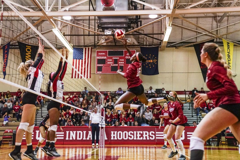 <p>Junior middle blocker Deyshia Lofton jumps up to return the ball against two Rutgers defenders Oct. 13 at University Gym. Lofton ranks fourth in school history for solo blocks.</p>