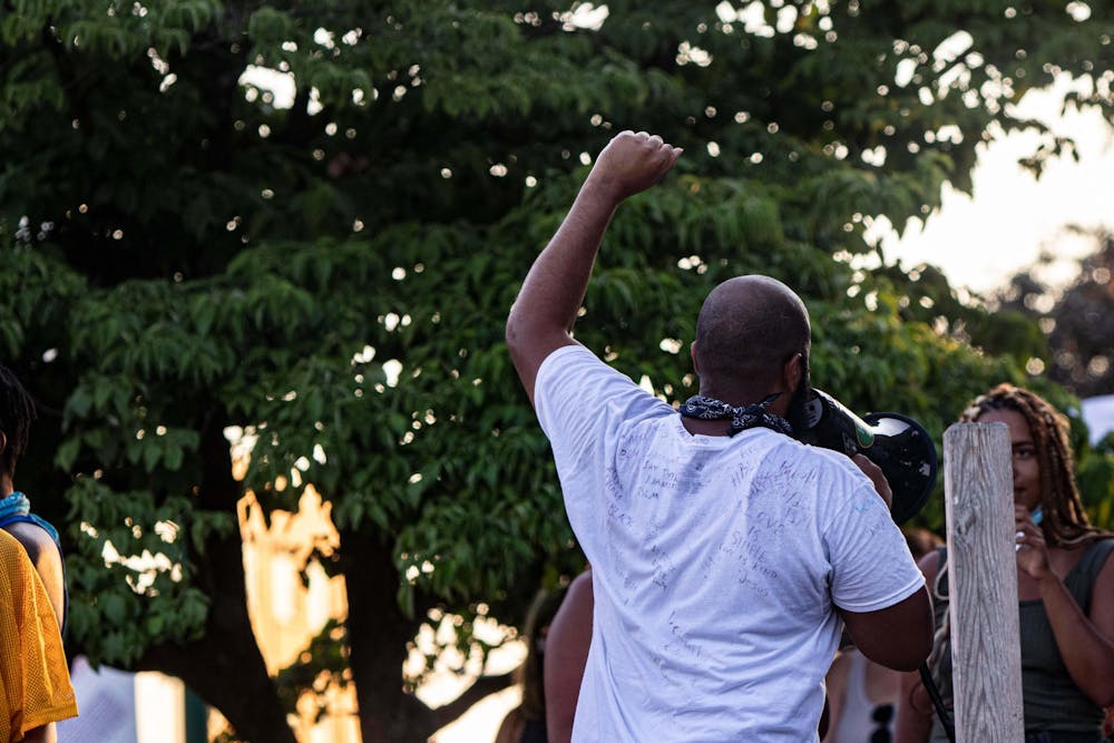 <p>A speaker raises his fist in the air after giving a speech July 7, 2020, in downtown Bloomington.</p>