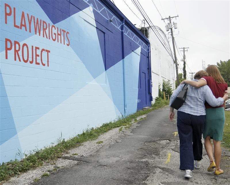 Laura Brikmanis, a 2001 IU graduate with a bachelor’s degree in English and studio art, shows her mom, Ellen Brikmanis from Carmel, Ind., her mural for the first time Friday outside of the Bloomington Playwrights Project.