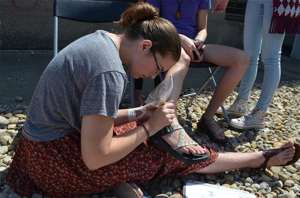 Rebecca Greenan, a Bloomington doula, draws on a girl's ankle using henna. As a doula, Greenan works with women to change the way that pregnancy and women are perceived.
