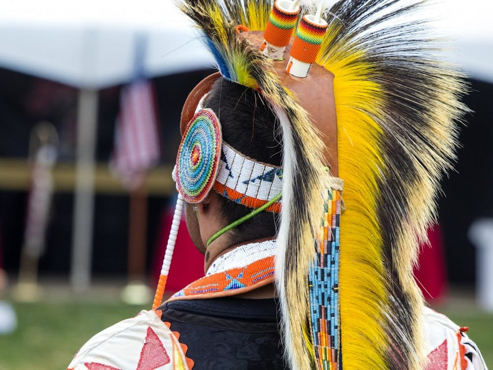 A man stands during the Grand Entry on April 6 at the IU Traditional Powwow in Dunn Meadow. The different styles of dance require different styles of regalia, Bella King said.
