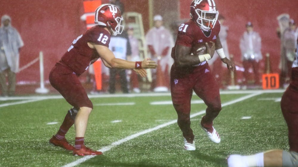 Freshman Stevie Scott takes the handoff from sophomore Peyton Ramsey in the pouring rain Sept. 8 at Memorial Stadium. Scott had 139 rushing yards for the Hoosiers in their loss to No. 4 Michigan on Saturday night.