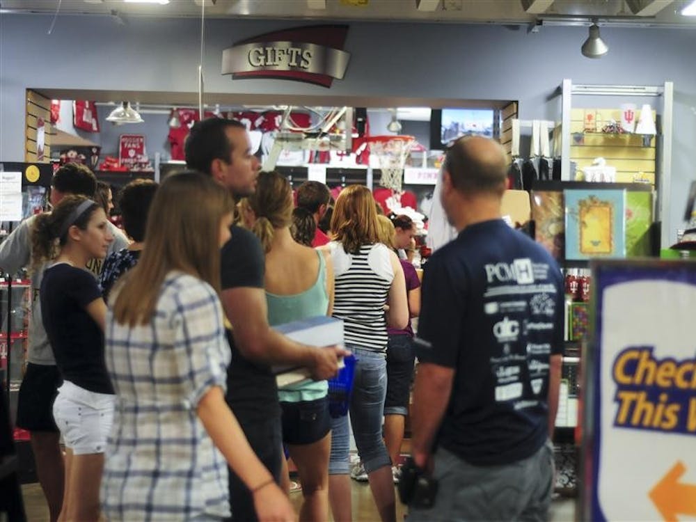 Shoppers wait in line to make their purchases Tuesday at TIS College Bookstore. In order to streamline the checkout process and reduce confusion TIS has placed signs telling shoppers where the checkout is located, as well as yellow arrows on the floor informing customers of the direction from which the line should form. 