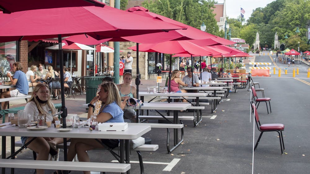 2020年8月29日，在柯克伍德大道，餐厅顾客坐在餐桌旁。周三，布卢明顿市中心的一些餐馆将户外座位扩大到封闭的停车位或parklets。