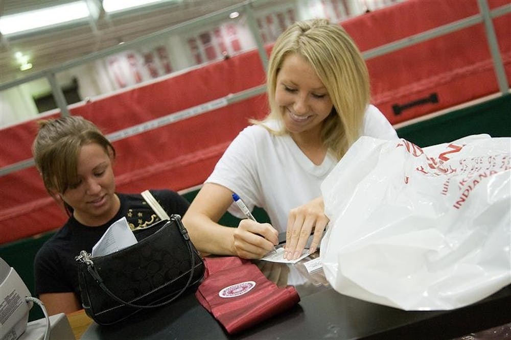 Seniors Amber Miller and Jill Prater pay for their caps and gowns Thursday morning at Gladstein Fieldhouse in preparation for IU's 180th Commencement on Saturday at Assembly Hall.