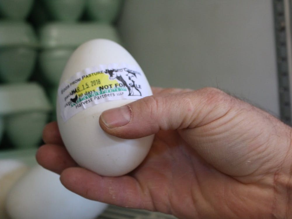 Farmer Larry Howard holds up an egg at Maple Valley Farm. Howard said the farm applies biomimicry to its methods in order to produce eggs and a variety of meats for its partners.&nbsp;