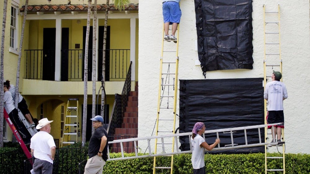 Employees at the Brazilian Court attach protective covers over windows in preparation for Hurricane Dorian on Aug. 28 in Palm Beach, Florida. Based on the current projections, Dorian is expected to turn into a Category 3 hurricane by Friday.