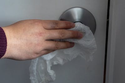 An IU student cleans a doorknob with a Clorex wipe. 