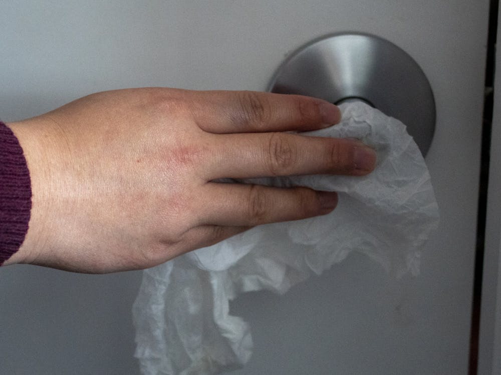 An IU student cleans a doorknob with a Clorex wipe. 
