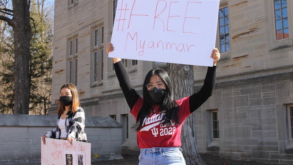 Sophomore Em Em and sophomore Dawt Hlei Iang hold signs at the Sit-In for Myanmar on Saturday at the Sample Gates. Students protested Saturday against the coup that occurred in Myanmar on Feb. 1. 