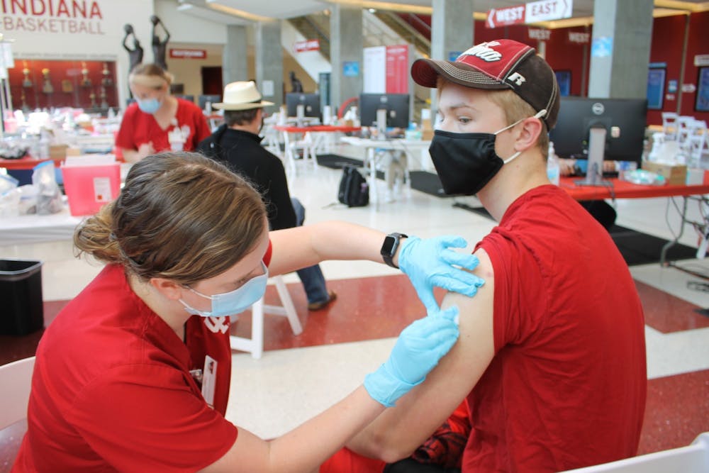 <p>Then-junior Bryce Asher gets his first dose of the COVID-19 vaccine, administered by nursing student Maddy Anderson, April 12 in Simon Skjodt Assembly Hall.</p>