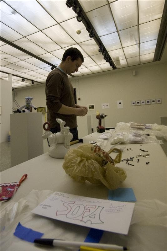 Fine Arts installation staff member Tyson Skross chooses what pieces he should next place in preparation for the SoFA Gallery Holiday Art Sale. The gallery opens to the public today, while bidding and buying will commence on Friday.