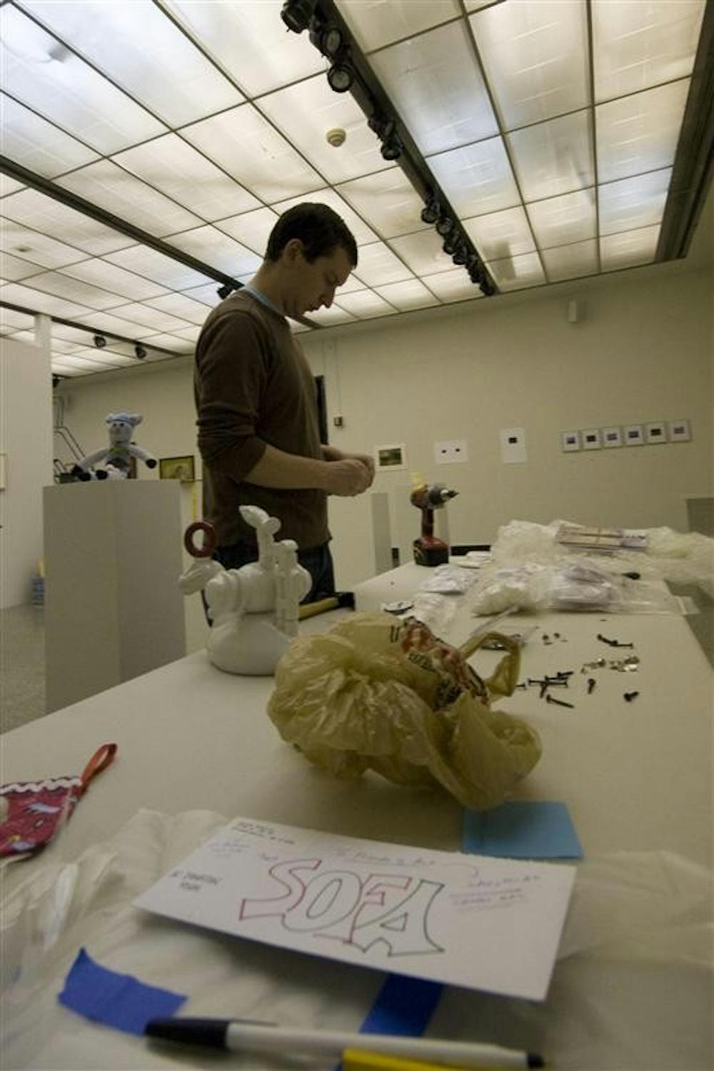 Fine Arts installation staff member Tyson Skross chooses what pieces he should next place in preparation for the SoFA Gallery Holiday Art Sale. The gallery opens to the public today, while bidding and buying will commence on Friday.