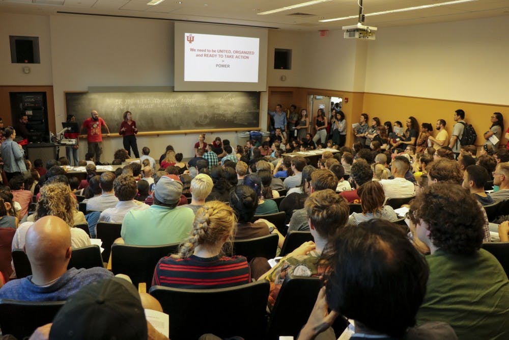<p>Students watch a presentation at the Indiana University Graduate Workers Coalition town hall Sept. 12 in the Lee Norvelle Theatre and Drama Center. The town hall addressed concerns raised by many graduate workers about the mandatory fees students are required to pay in order to work and learn at IU.</p>