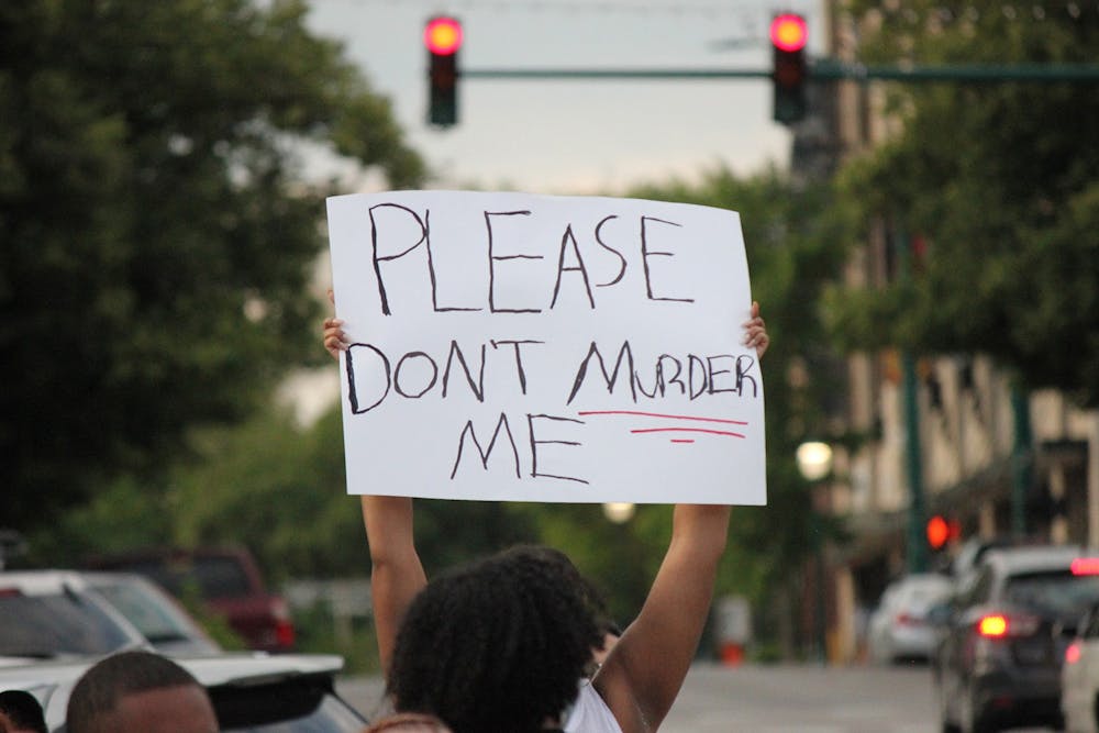 6月1日，一名抗议者在布卢明顿市中心高举标语。乔治·弗洛伊德'；他死于明尼阿波利斯警官德里克·乔文之手。
