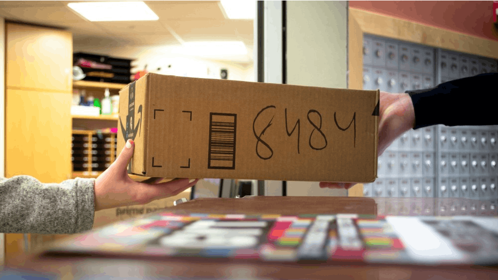 中心办公桌的一名员工将一个包裹递给一名学生。毒品贩子信任美国邮政服务将毒品运送到全国各地，包括IU。