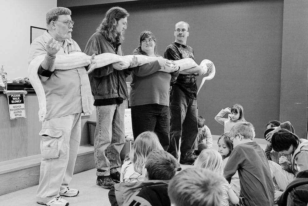 “Snakehead Ed” and three audience volunteers hold Melvin, an Albino Burmese Python, while children ask questions Saturday afternoon at Wonderlab. The program, “Snakes Alive & More!”, sought to educate audience members about different snake species and dispell prevailing myths about snakes.