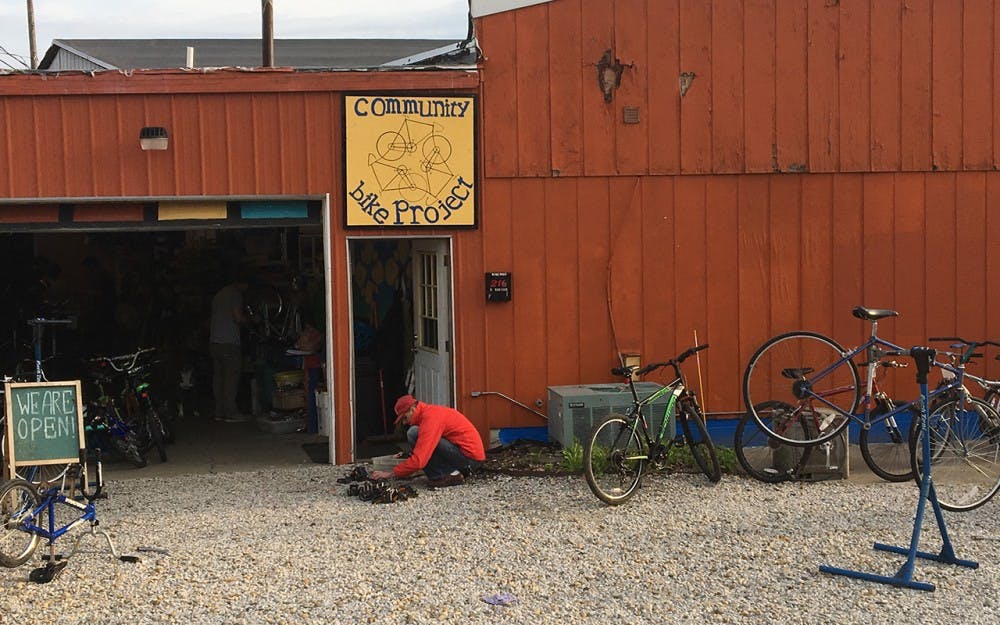A Bloomington Community Bike Project patron looks through a drawer of bike parts, searching for a new pedal. The shop offers free tools and parts for people to repair bikes.