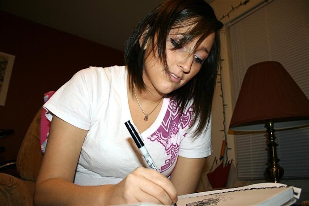 Junior Kara Jeffers designs the logo for her line of T-shirts Jan. 19 in the living room of her apartment. Her current line of T-shirts is one year old.