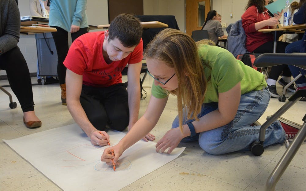 Senior Nick Gauss and sophomore Cara Yoder work with their group to draw an ideal superhero. Each person in the group wrote down traits of good heroes before coming together for a final creation.