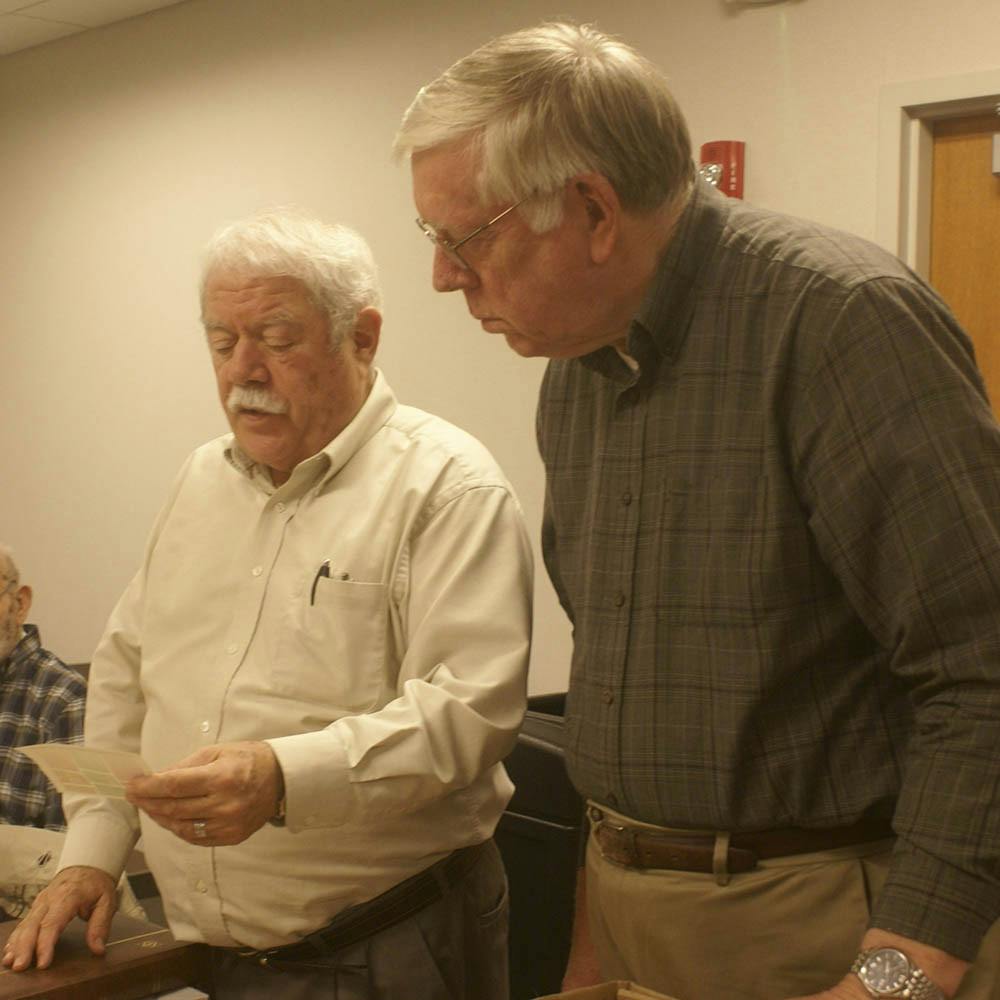 Mark Goodson and Doug Tracy look at stamps they will organize for the members at next month's meeting Wednesday evening at the Monroe County Public Library. The members have the option to trade and buy stamps from each other at each meeting. 