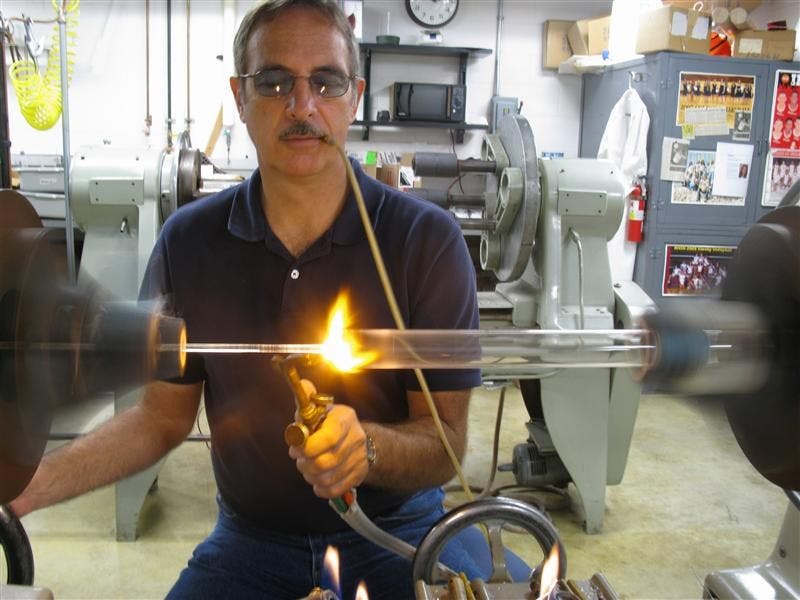 IU glassblower Don Garvin blows into a tube as he spins glass on a lathe Oct. 14 at the IU Glass Shop. Garvin is one of three university glassblowers in the state.