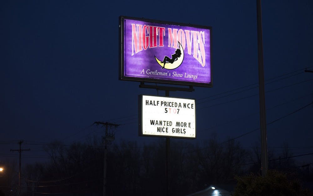 The Nightmoves road sign glows Sunday night. The strip club, located on Walnut St., was recently bought by the city.