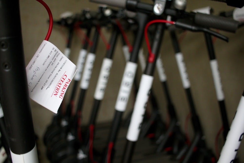 <p>Impounded Bird scooters have parking citation notes posted on them. The scooters are currently being held in a storage room at the Poplars Parking Garage.</p>