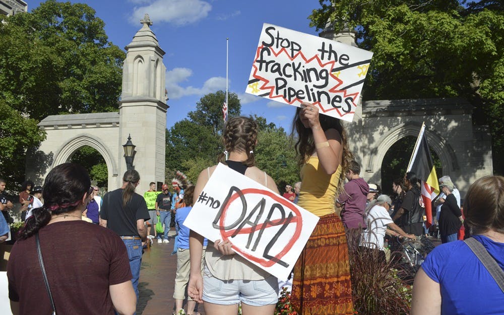 Students, Bloomington residents and Native American activists hold up signs by Sample Gates Sunday evening protesting the Dakota Access Pipeline. The rally was held following news Saturday that the government would temporaily hault work on the Dokota Access Pipeline.