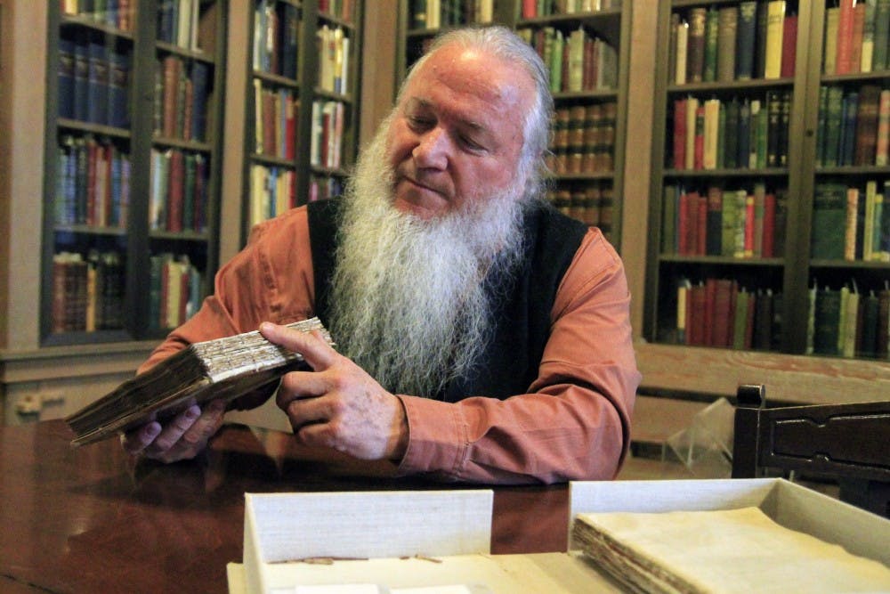 Conservator Jim Canary explains how he plans to repair the binding of a book that is currently kept in a cardboard box. Canary conducts repairs in the Lilly Library’s conservation lab.
