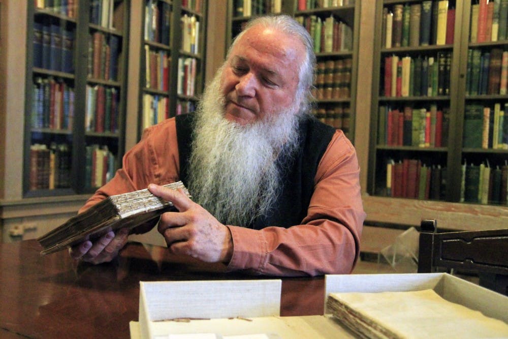 <p>Conservator Jim Canary explains how he plans to repair the binding of a book that is currently kept in a cardboard box. Canary conducts repairs in the Lilly Library’s conservation lab.</p>