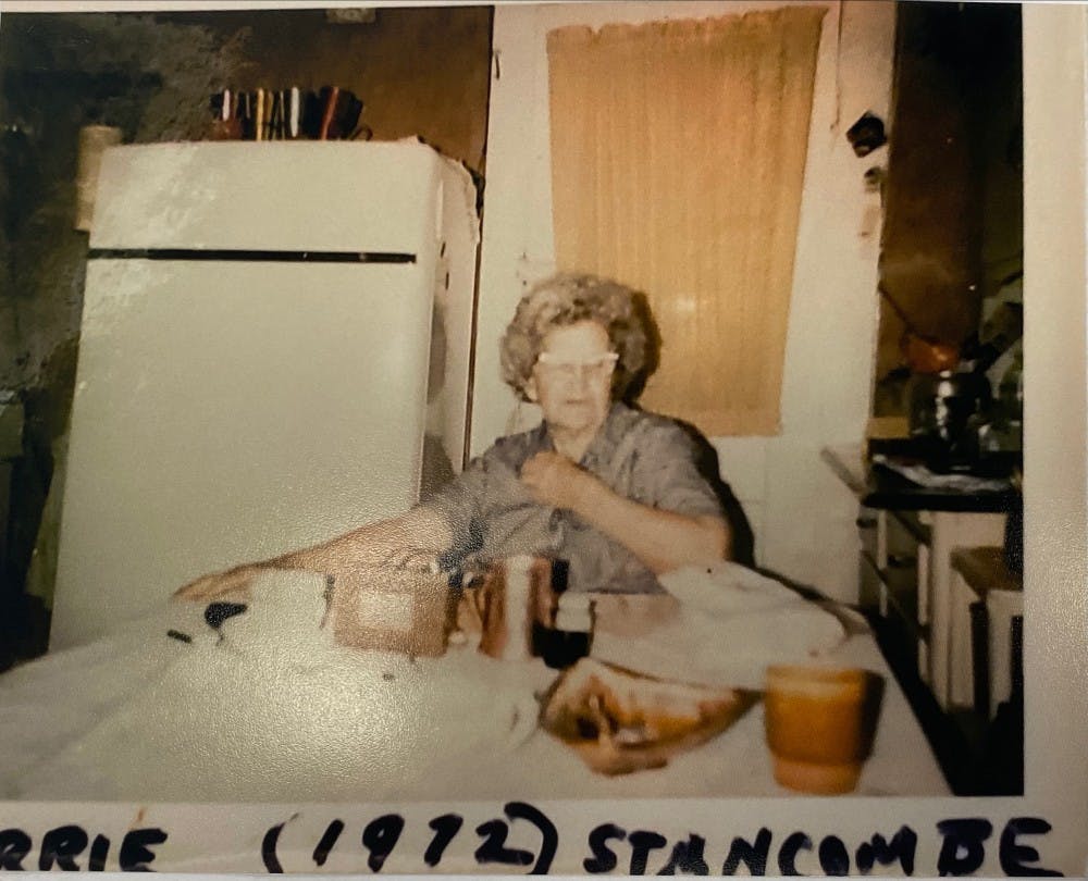 Carrie Stancombe sits at the dining room table of her house in 1972 at 523 W. 7th St. Aluminum cups can be seen on top of the fridge, and they would rattle when people walked in.