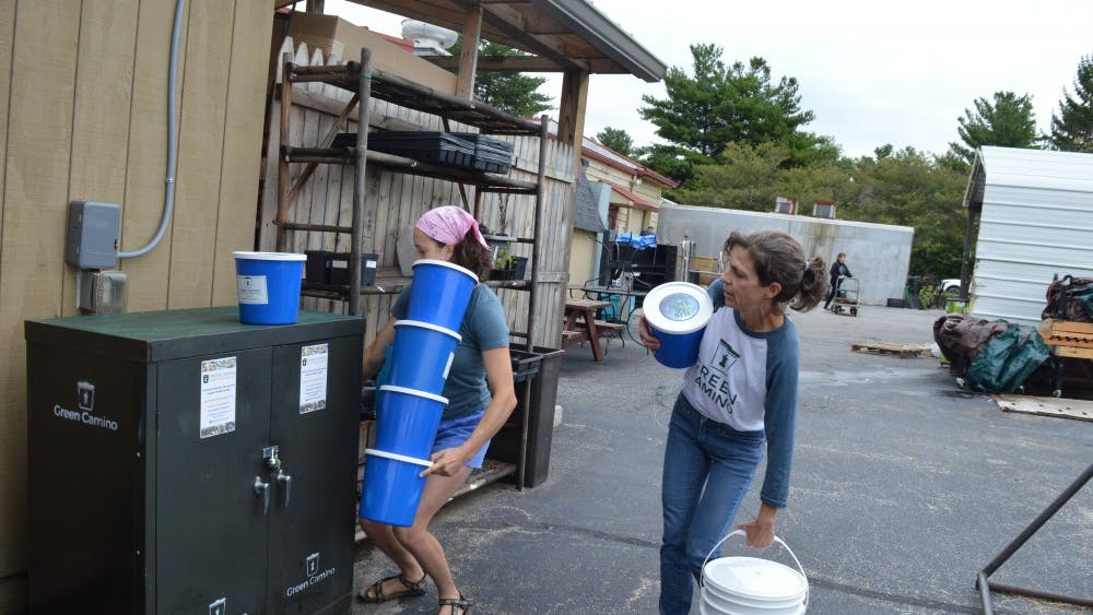 Green Camino, a curbside composting company, co-founder Kathy Gutowsky and employee Maggie Gates take empty pails from the drop off site next to Bloomingfoods East. Green Camino washes every pail by hand, and customers receive a clean one each time.&nbsp;