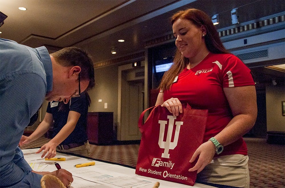 Jordan Spoor, a senior student who studies Elementary Education, helps a student parent to sign in on Monday afternoon at the Indiana University Auditorium. She was one of the program leaders on new student orientation team.