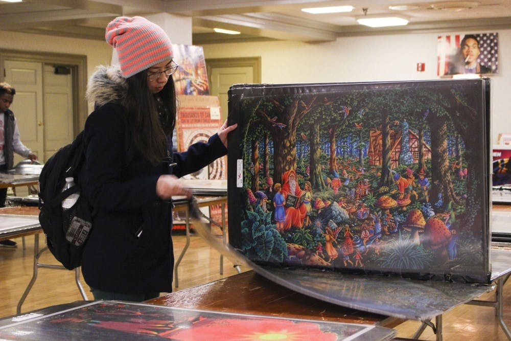 Freshman Jelena Nguyen looks through the giant folders of posters on the center tables. The Indiana Memorial Union is doing a poster sale this week, Jan. 8-12 from 9 a.m. to 6 p.m. in the Georgian room.