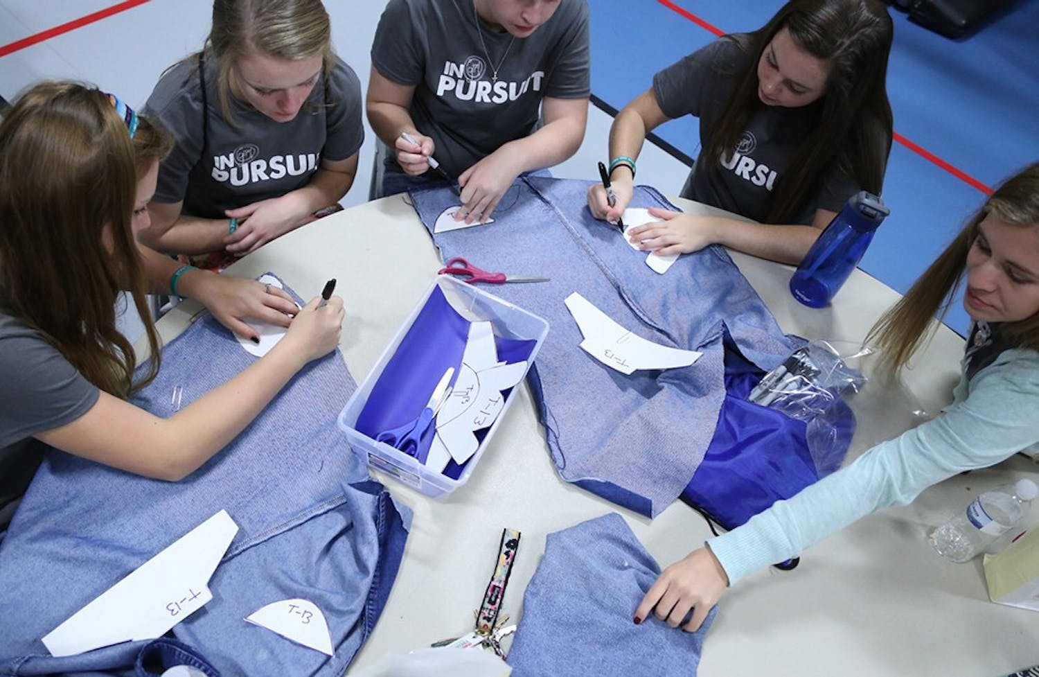 Girls cut jeans at the One Girl conference at Sherwood Oaks Christian Church to be made into shoes for Ugandans in poverty on Saturday afternoon.