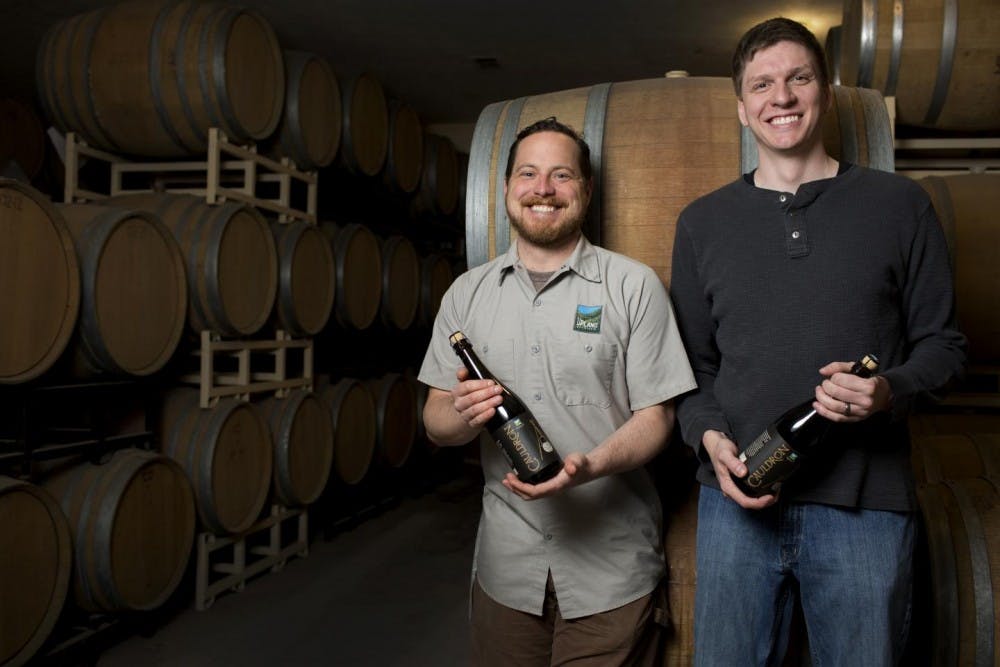 IU biochemist Matthew Bochman, right, and Caleb Staton of Upland Brewing Co. in front of the barrels used to age sour beers. Bochman collaborated with Upland to develop an improved method to create sour beers. 