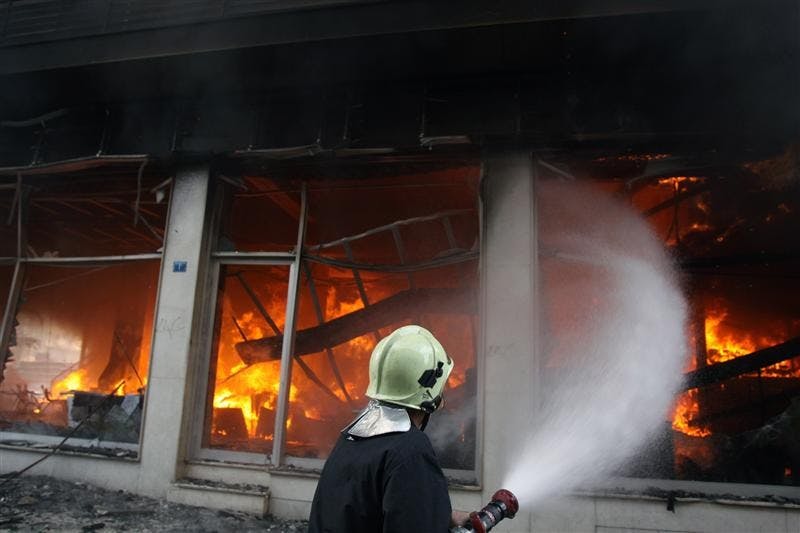 A firefighter tries to extinguish a burning Emporiki Bank branch during clashes on Sunday in central Athens. Riots broke out Sunday in the Greek capital as demonstrators protested the fatal police shooting of a teenager in Athens the previous night. Youths hurled firebombs, rocks and other objects at riot police, who responded with tear gas. 