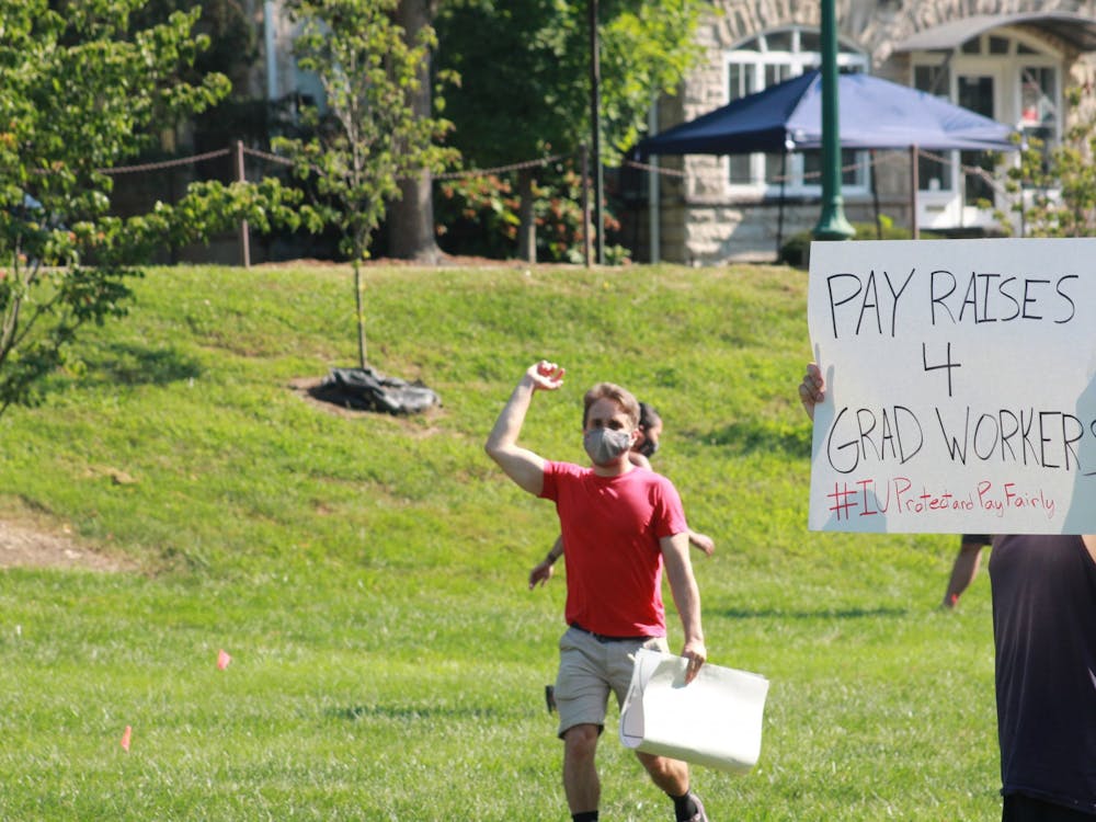 A protester holds a “PAY RAISES 4 GRAD WORKERS” sign during a protest regarding inadequate pay Aug. 24, 2020, in Dunn Meadow. The Indiana United Graduate Workers Coalition Electric Workers submitted a cost-of-living adjustment petition to IU administration calling for an 8% salary increase.