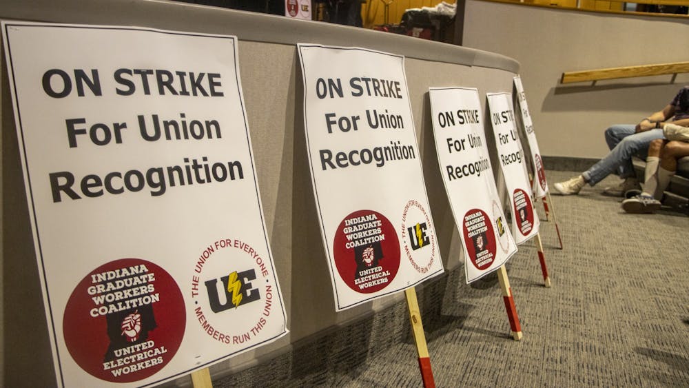 Signs are laid in front of the Monroe County Public Library auditorium stage at an in-person vote for the Indiana Graduate Workers Coalition-United Electrical Workers to go on strike April 10, 2022﻿. The IGWC-UE is set to vote Sept. 25 to decide whether or not to resume their strike, which was suspended over the summer.