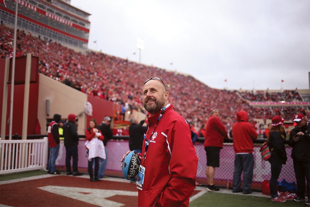 Jeremy Gray, an associate athletic director at IU Athletics, pauses while playing catch with his son in Knot Hole Park during the Ohio State game on Saturday to look up at the video board. Gray's job entails making a good fan experience at games to grow the fan base. 