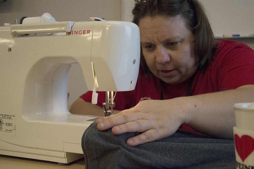 Jenett Tillotson sews the ends of an oversized T-shirt as she attempts to make it into a shopping bag during the Discardia Mending Day Saturday at the Monroe County Public Library. 
