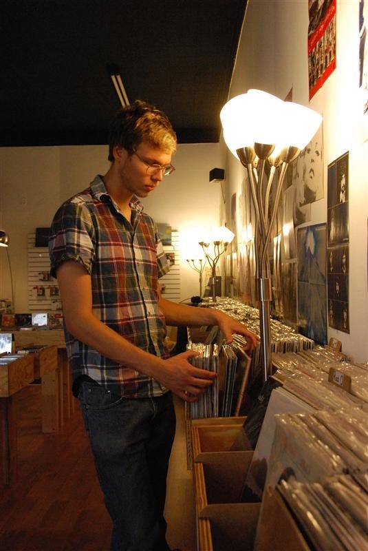 IU student Anson Hohne, 20, flips through a stack of vinyl LPs on Monday afternoon at Landlocked Music. The music shop, which opened in the spring of 2006, moved to North Walnut Street just north of the Bloomington square in July.