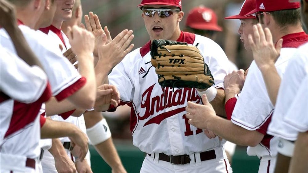 Senior Michael Earley high-fives teammates as he takes the field before IU's 16-10 loss to Michigan Sunday, April 4 at Sembower Field.